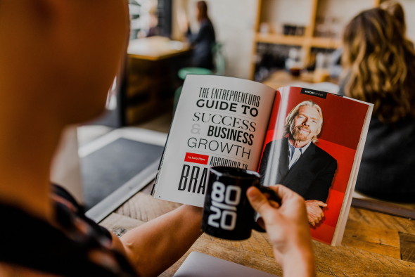 A man reading a business book over coffee. Richard Branson is pictured.